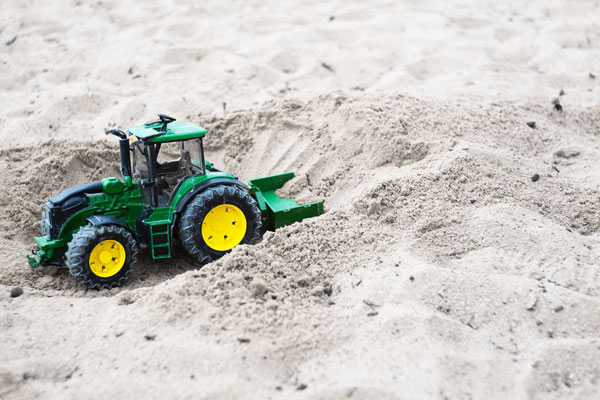 kleiner Spielzeug Traktor im Quarzsand